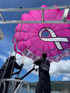 Close up of two crew members opening up pink Catalina Xtreme Parasail parachute from the boat on a sunny day